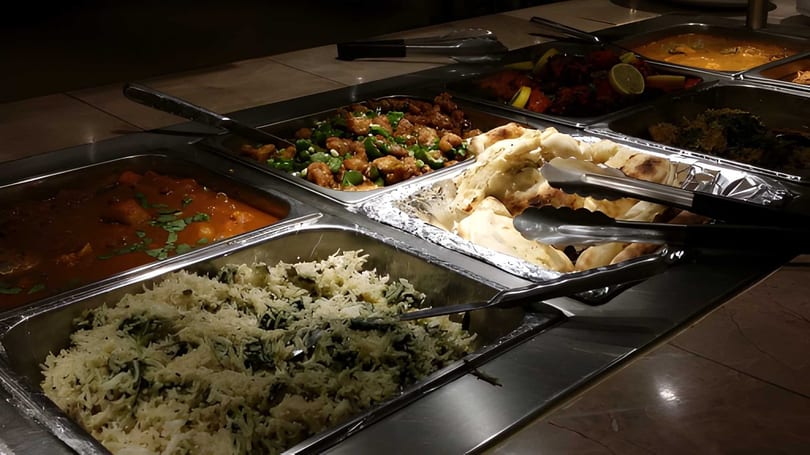 A buffet spread with various Indian dishes including curries, rice, naan bread, and chicken.